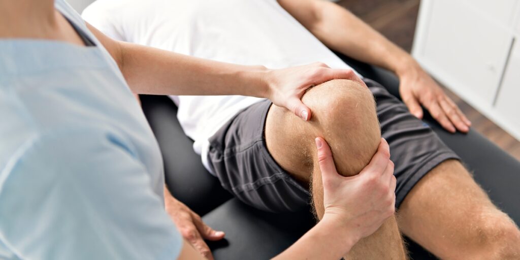 man having knee treatment with physiotherapist